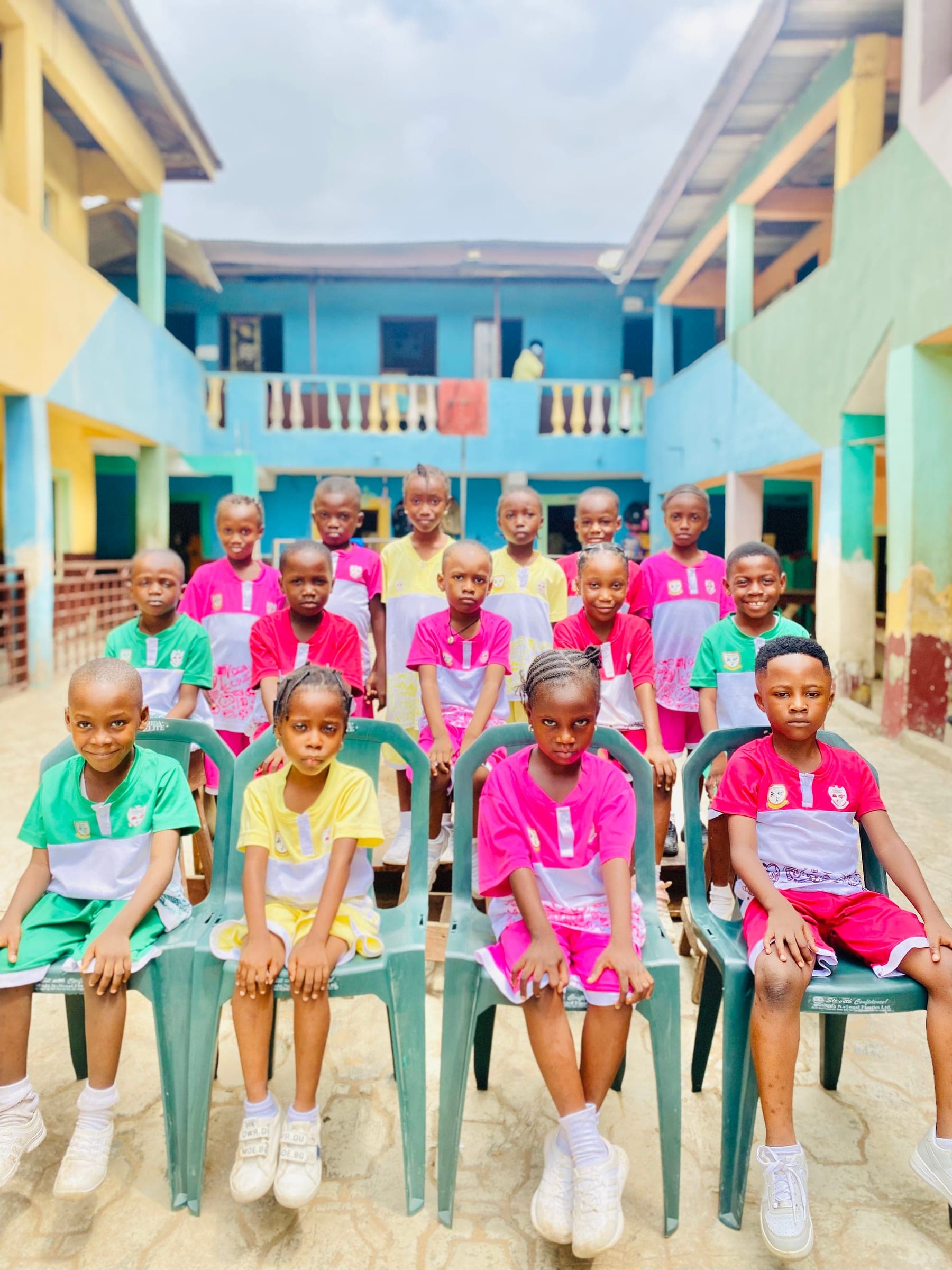 Young pupils in coloured house sports kit seated in the courtyard